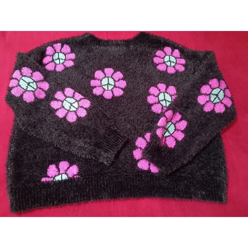 This is a Justice girls' black fuzzy eyelash sweater featuring pink and blue...